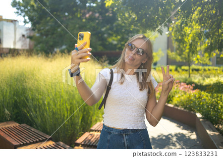 Cheerful smiling 30s lady taking selfie outdoors in city park, happy young female capturing self-portrait while enjoying walk and good day, resting outside Cheerful smiling 30s lady taking selfie outdoors in city park, happy young female capturing self-portrait while enjoying walk and good day, resting outside 123833231