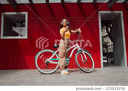 Woman, city bike and phone headphones for music, podcast of radio in Colombian travel. Smile, happy and fashion student or cool model with mobile, eco friendly and future environment energy transport 123833258