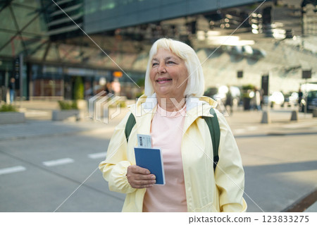 Senior female tourist in airport hold passport ticket schedule to check flight departure gate. Travel and tourism concept, people with backpack on shoulders. Senior female tourist in airport hold passport ticket schedule to check flight departure gate. Travel and tourism concept, people with backpack on shoulders. 123833275