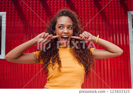 Fashion, summer and woman with smile on red background in city. Beauty, freedom and happy girl on holiday touching face in cute, silly and goofy pose. Excited, happiness and adventure in urban town Fashion, summer and woman with smile on red background in city. Beauty, freedom and happy girl on holiday touching face in cute, silly and goofy pose. Excited, happiness and adventure in urban town 123833325