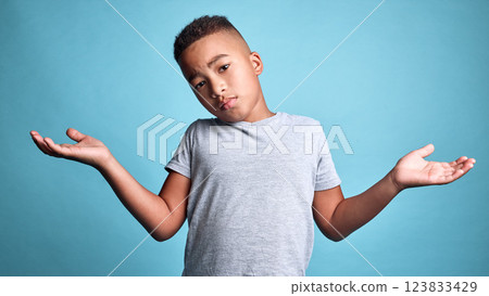 Doubt, question and shrug from child with confused facial expression, dont know gesture and raised hands. Young boy, African youth and face portrait of puzzled black kid isolated on blue background Doubt, question and shrug from child with confused facial expression, dont know gesture and raised hands. Young boy, African youth and face portrait of puzzled black kid isolated on blue background 123833429