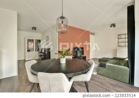 A bright and inviting living area featuring a round dining table, comfortable seating, and stylish decor, perfect for relaxation and social gatherings. 123833514