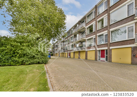 A scenic view of a residential street lined with greenery and modern apartments. The area features a calm atmosphere with well-maintained surroundings. A scenic view of a residential street lined with greenery and modern apartments. The area features a calm atmosphere with well-maintained surroundings. 123833520