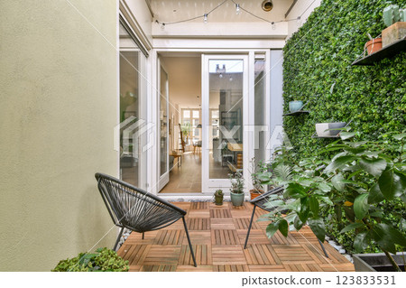 Bright and inviting garden area featuring lush plants, a stylish seating arrangement, and natural light flooding through large windows, perfect for relaxation. 123833531