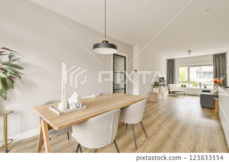 Charming modern interior featuring a stylish dining area with a minimalist table, elegant chairs, and a bright window view that enhances the ambiance. 123833554