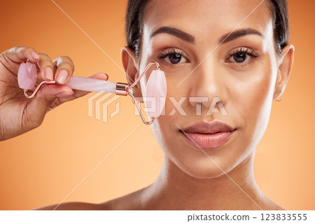 Woman, beauty and makeup roller tool for cosmetic luxury face skincare health on an orange studio background. Facial massage accessory, anti aging firming cosmetics routine and healthy skin wellness Woman, beauty and makeup roller tool for cosmetic luxury face skincare health on an orange studio background. Facial massage accessory, anti aging firming cosmetics routine and healthy skin wellness 123833555