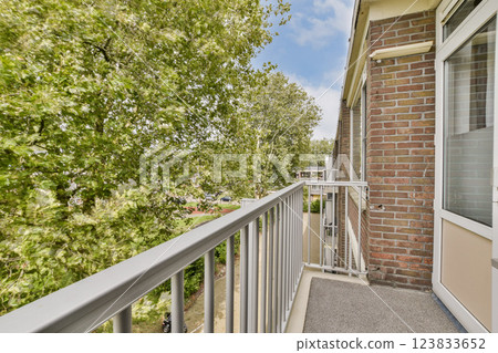 A bright balcony overlooking lush green trees, creating a serene and peaceful atmosphere. Ideal for relaxation and enjoying nature. A bright balcony overlooking lush green trees, creating a serene and peaceful atmosphere. Ideal for relaxation and enjoying nature. 123833652