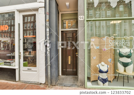 A quaint street scene showcasing a stylish boutique with lingerie displayed prominently, juxtaposed against a traditional building entrance. A quaint street scene showcasing a stylish boutique with lingerie displayed prominently, juxtaposed against a traditional building entrance. 123833702