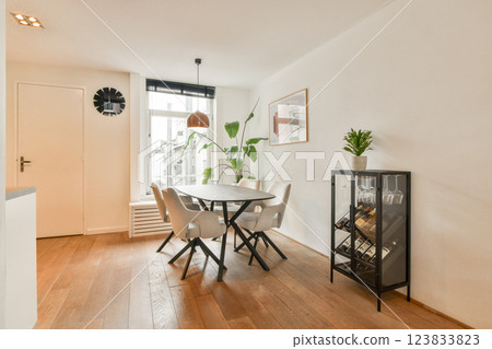 A stylish dining area featuring minimalistic furniture, natural light, and decorative plants, perfect for casual meals and gatherings. A stylish dining area featuring minimalistic furniture, natural light, and decorative plants, perfect for casual meals and gatherings. 123833823