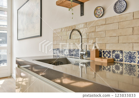 A stylish modern kitchen featuring a sleek countertop, decorative tiles, and minimalistic design elements. The space blends functionality and aesthetics effortlessly. A stylish modern kitchen featuring a sleek countertop, decorative tiles, and minimalistic design elements. The space blends functionality and aesthetics effortlessly. 123833833