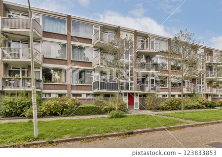 An elegant modern residential building surrounded by lush greenery and well-maintained landscaping. Architectural features enhance its contemporary look. 123833853