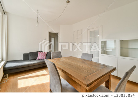 A minimalist modern living room featuring a wooden table and stylish sofas. Natural light streams in, creating a warm and inviting atmosphere. A minimalist modern living room featuring a wooden table and stylish sofas. Natural light streams in, creating a warm and inviting atmosphere. 123833854