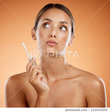Skincare, beauty product and woman holding makeup brush for lipstick, gloss and cosmetics for shine. Female thinking of dermatology or cosmetology skin treatment against orange studio background Skincare, beauty product and woman holding makeup brush for lipstick, gloss and cosmetics for shine. Female thinking of dermatology or cosmetology skin treatment against orange studio background 123833893