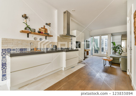 A stylish modern kitchen featuring sleek cabinetry, wooden flooring, and large windows that bring in natural light, creating an open and inviting atmosphere. A stylish modern kitchen featuring sleek cabinetry, wooden flooring, and large windows that bring in natural light, creating an open and inviting atmosphere. 123833894