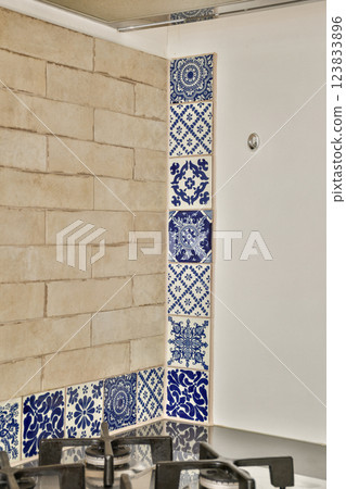 A modern kitchen showcasing a striking backsplash featuring intricate blue and white decorative tiles. The combination enhances the contemporary aesthetic. A modern kitchen showcasing a striking backsplash featuring intricate blue and white decorative tiles. The combination enhances the contemporary aesthetic. 123833896