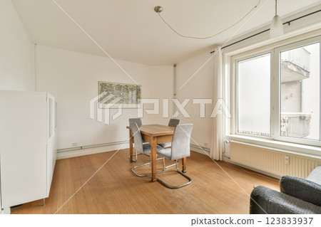 A modern interior showcasing a dining area with a minimalist style. Features a simple table, chairs, and a large window allowing natural light. A modern interior showcasing a dining area with a minimalist style. Features a simple table, chairs, and a large window allowing natural light. 123833937