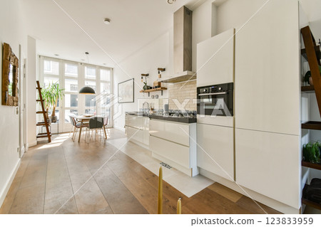 Stylish and spacious kitchen featuring sleek cabinetry, bright natural light, and a minimalist design that promotes functionality and elegance. 123833959