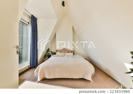 A stylish bedroom featuring a soft bed, minimalistic design, and large windows allowing ample natural light, creating a serene atmosphere. A stylish bedroom featuring a soft bed, minimalistic design, and large windows allowing ample natural light, creating a serene atmosphere. 123833960