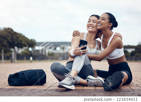 Workout, happy and friends with phone on floor after fitness training in the city of New York together. Runner and black woman talking about funny 5g mobile app after health exercise outdoor 123834011