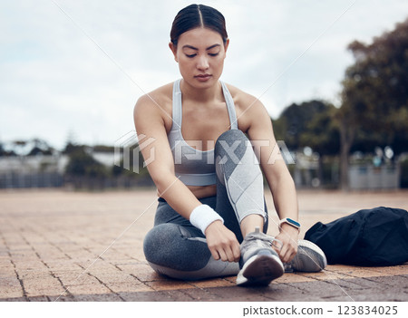 Fitness, sports and woman with shoes ready to start running outdoors for exercise, raining and cardio workout. Young, tying and healthy girl runner with preparing footwear laces for marathon training 123834025