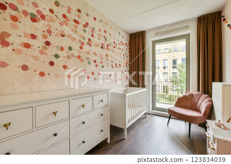 Bright and inviting nursery featuring a unique polka dot wall design, a crib, and soft furnishings that create a warm atmosphere for a child. 123834039