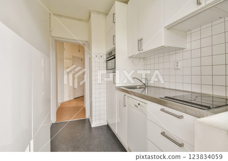 A sleek and modern kitchen featuring white cabinets, minimalist appliances, and a clean aesthetic that maximizes space and functionality. 123834059