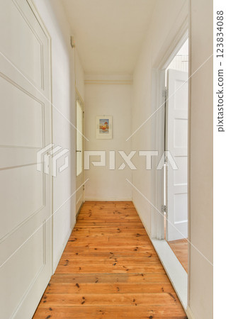 A bright and airy hallway showcasing wooden flooring and white walls, leading to an open door inviting natural light, creating a warm atmosphere. A bright and airy hallway showcasing wooden flooring and white walls, leading to an open door inviting natural light, creating a warm atmosphere. 123834088