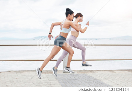 Running, fitness and fast women doing sprint challenge by ocean, sea promenade or beach for outdoor wellness, exercise or cardio workout. Sports athlete people train for speed and a healthy lifestyle 123834124