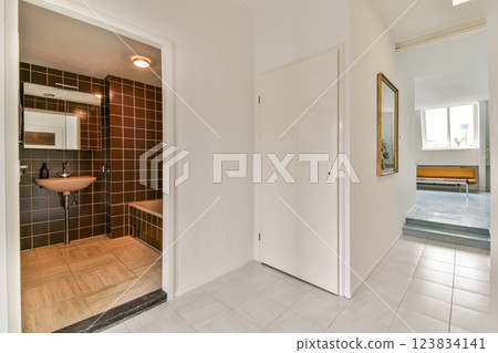 A sleek and modern interior hallway showcasing a blend of minimalist design elements, contrasting color schemes, and functional space. A view into a well-lit area enhances the aesthetic. 123834141