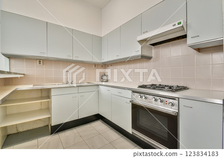 A sleek and contemporary kitchen featuring minimalist cabinets, a professional stove, and tiled flooring, ideal for cooking and entertaining. A sleek and contemporary kitchen featuring minimalist cabinets, a professional stove, and tiled flooring, ideal for cooking and entertaining. 123834183