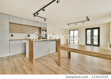 A sleek, modern kitchen featuring light wood and grey cabinetry. The open space, natural light, and minimalistic design create a fresh and inviting atmosphere. A sleek, modern kitchen featuring light wood and grey cabinetry. The open space, natural light, and minimalistic design create a fresh and inviting atmosphere. 123834185