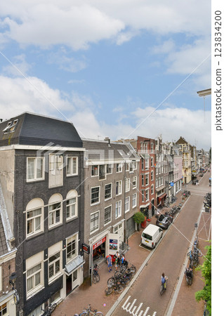 A picturesque view of traditional Dutch architecture lining a serene canal in Amsterdam, showcasing vibrant facades and a bustling street life. 123834200