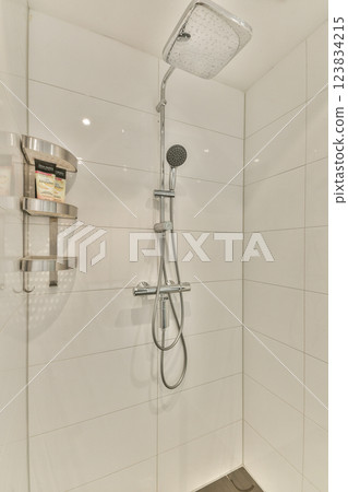 A sleek and contemporary shower setup featuring polished tiles and a stylish showerhead. The minimalist design enhances the overall aesthetic of the space. 123834215