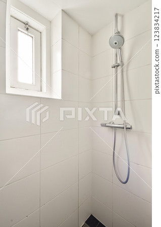 A sleek and clean shower area featuring white tiled walls and contemporary fixtures, perfect for a minimalist bathroom design. A sleek and clean shower area featuring white tiled walls and contemporary fixtures, perfect for a minimalist bathroom design. 123834217