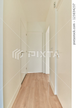 A spacious, bright hallway showcasing a minimalist design with light wooden flooring and white walls, creating a modern aesthetic. A spacious, bright hallway showcasing a minimalist design with light wooden flooring and white walls, creating a modern aesthetic. 123834237
