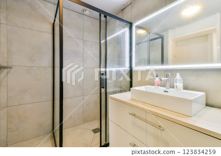 A sleek modern bathroom featuring a glass shower, stylish sink, and contemporary cabinetry, combining functionality with aesthetic appeal. 123834259