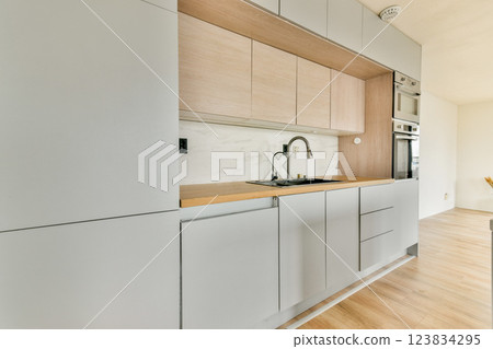 A sleek and modern kitchen featuring minimalist cabinetry and a spacious layout, showcasing a blend of functionality and contemporary aesthetics. 123834295