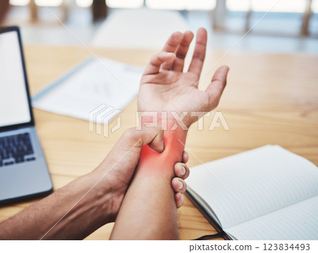 Businessman, wrist pain and injury at desk working, planning and writing in workplace with laptop. Painful muscle, male hand and overworked from typing with sore arm, notebook at work table. Businessman, wrist pain and injury at desk working, planning and writing in workplace with laptop. Painful muscle, male hand and overworked from typing with sore arm, notebook at work table. 123834493