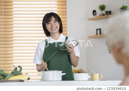 A woman in her 30s and a senior woman cooking in the kitchen Image of a housekeeping service A woman in her 30s and a senior woman cooking in the kitchen Image of a housekeeping service 123834618