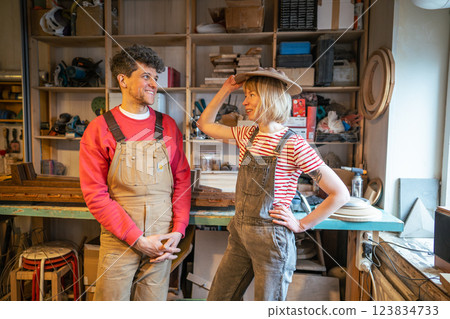 Cheerful family of carpenters playfully try on woo lampshade as hat in workshop, leisure at work Cheerful family of carpenters playfully try on woo lampshade as hat in workshop, leisure at work 123834733