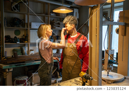 Cheerful family of carpenters having fun and joy in workshop, playful moment during work break Cheerful family of carpenters having fun and joy in workshop, playful moment during work break 123835124