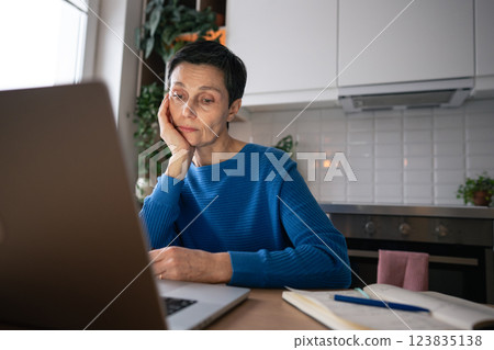 Tired mature woman overwhelmed by laptop work even at home. Remote work burnout, depression, stress 123835138