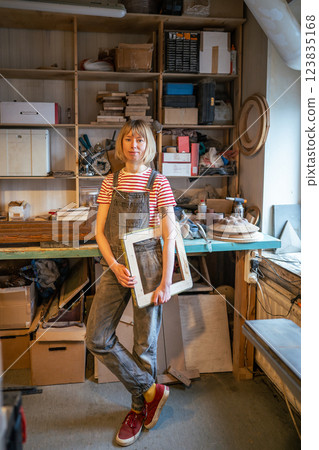Relaxed thoughtful woman carpenter take break holding piece wooden handmade product in joiner shop. 123835168