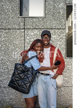Happy African American siblings cuddlling, look at camera with smiles near wall. Weekend stroll Happy African American siblings cuddlling, look at camera with smiles near wall. Weekend stroll 123835198