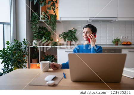 Relaxed smiling woman enjoy morning tea, consulting clients on phone. Freelancer working on calls Relaxed smiling woman enjoy morning tea, consulting clients on phone. Freelancer working on calls 123835231