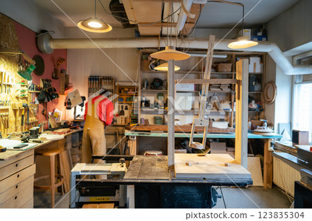 Rearview of busy carpenter preparing tools for woodworking in workshop, setting up machinery 123835304