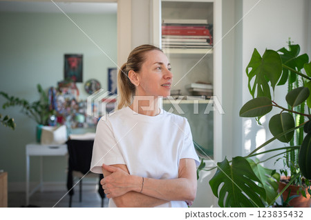 Dreamful looking woman spending slow morning for affirmations, deep thoughts calm standing at home 123835432