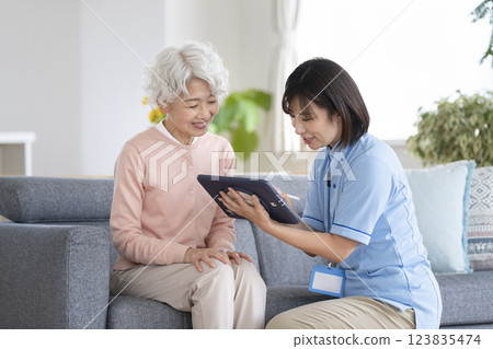 護理人員正用平板電腦聆聽一位老年婦女的傾訴 123835474