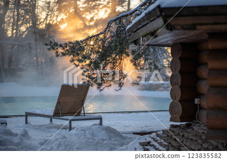 Open-air swimming pool with warm water, loungers and wooden Russian bath in sunny cold weather 123835582