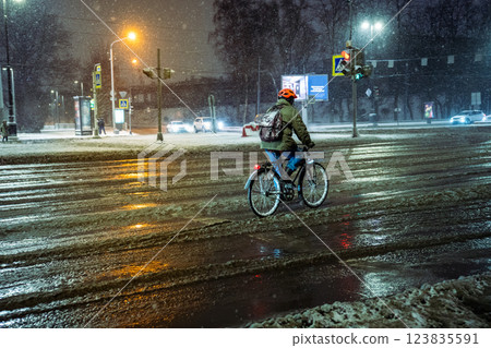 Bicyclist rides through dense traffic amid intense snowstorm facing slush covered unplowed roads Bicyclist rides through dense traffic amid intense snowstorm facing slush covered unplowed roads 123835591